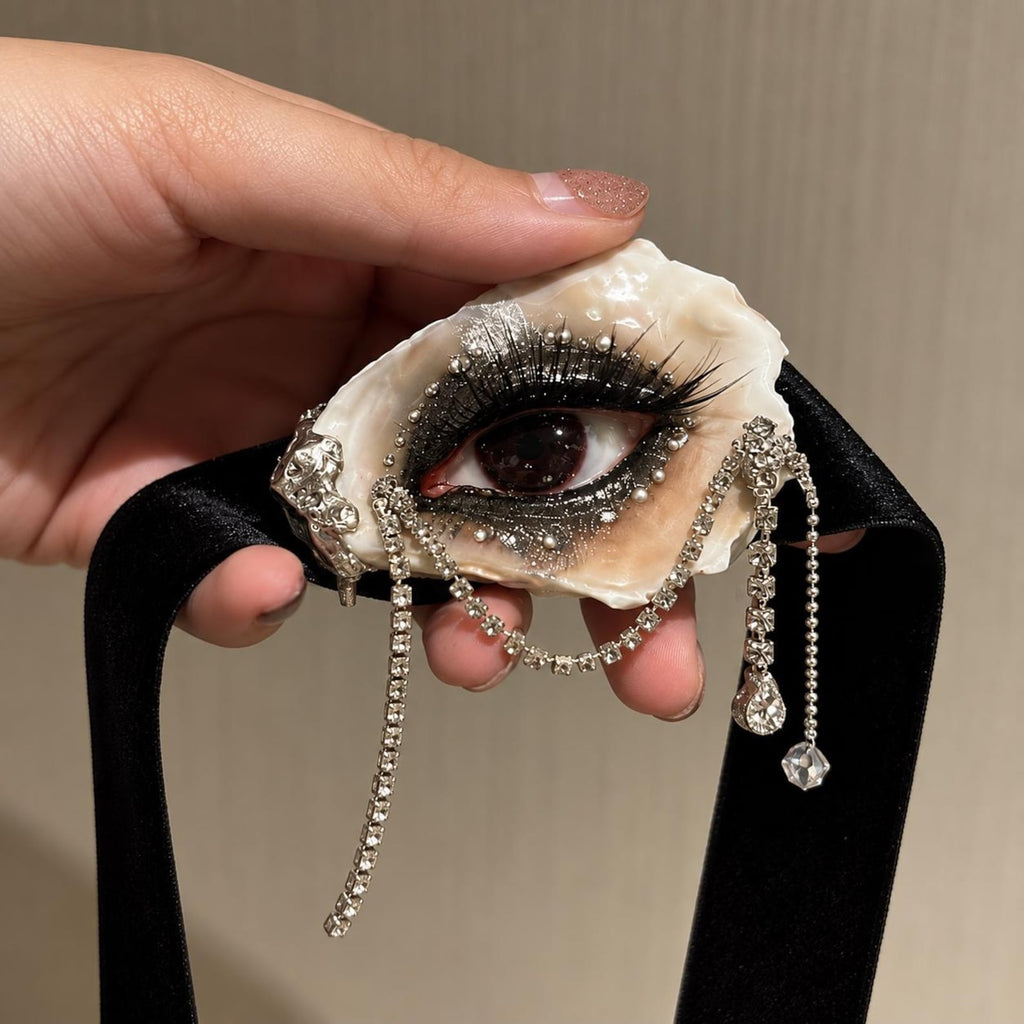 LV029 — handheld black velvet choker showing the deep red eye and dangling ornaments