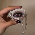 Close-up of Lilith Veil red-pupil oyster eye held in hand with faux pearls and silver chain drapes